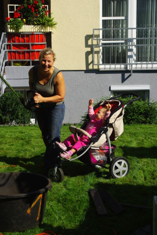 Gärtnerin mit Kind im Kinderwagen im Garten